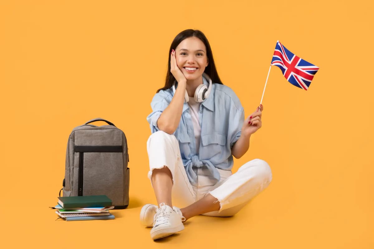 A student holding a small Union Jack, with a backpack and notebooks