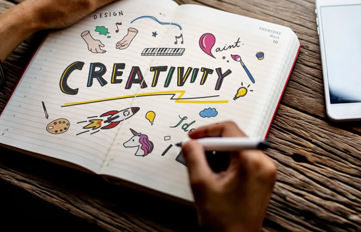 A hand writing and sketching in an open notebook